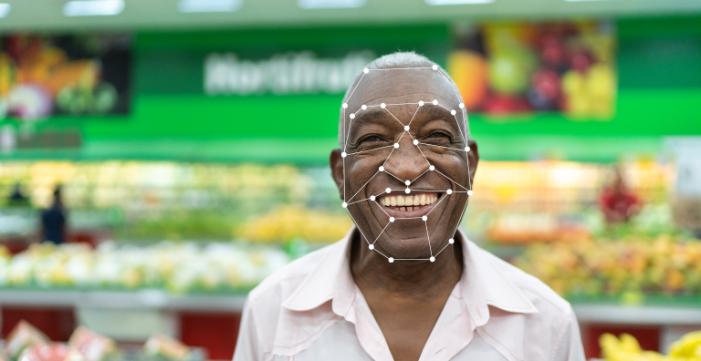 一位杂货店的顾客微笑着，脸上挂着面部识别图像。